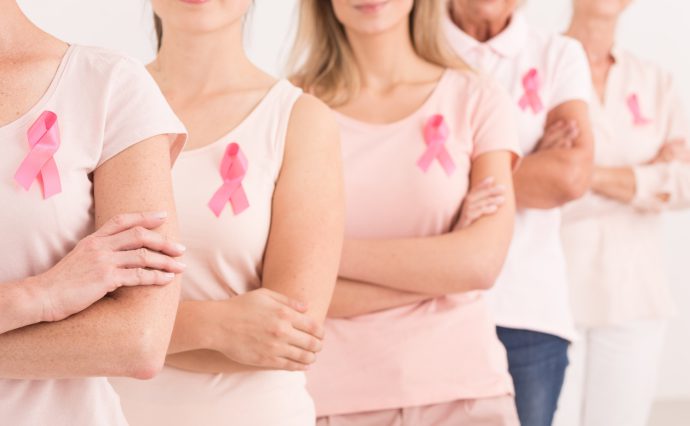 The power to fight breast cancer, women wearing pink ribbons for breast cancer campaign on white background